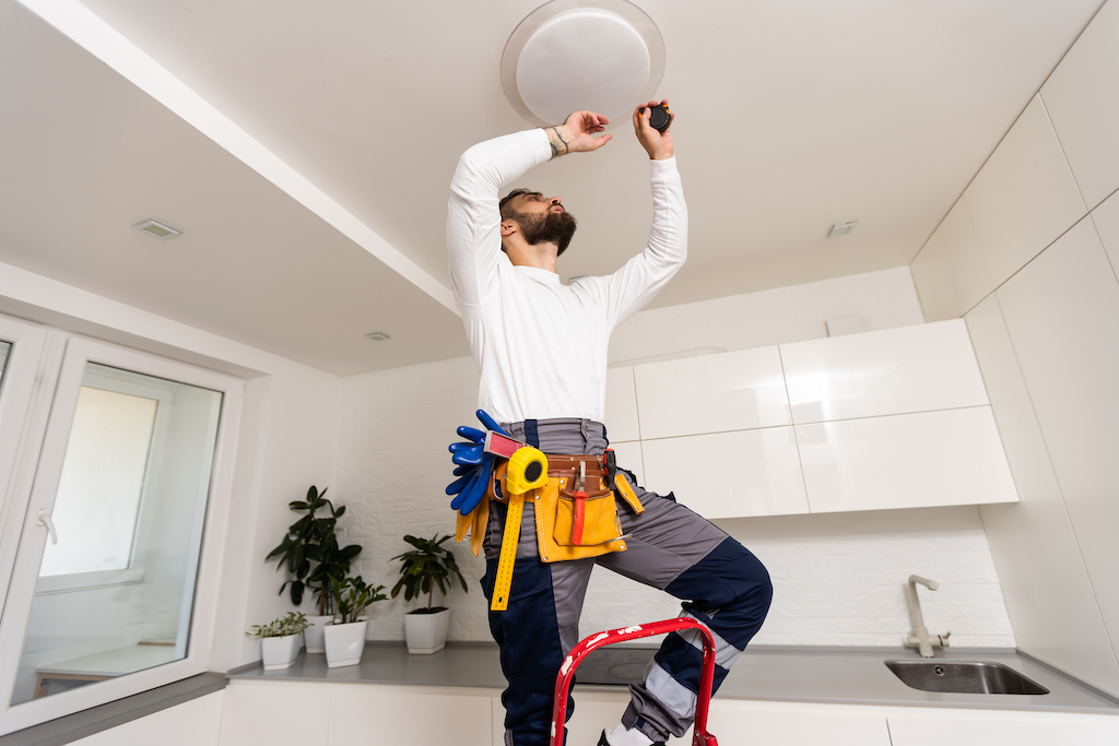 Electrician worker installation electric lamps light inside apartment. 