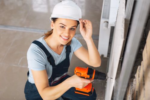 A woman wearing a safety helmet is engaged in a DIY building project.