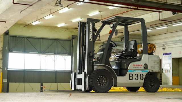 A grey Nissan Forklift, inside of a warehouse building
