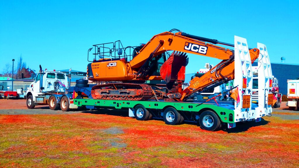 large truck and trailer moving digger for new home construction