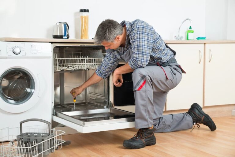 Tradie Repairing Dishwasher With Screwdriver In Kitchen