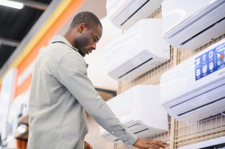 A man evaluating heat pumps on display in an appliance store, considering options for home heating and cooling.