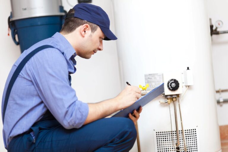 A licensed gas fitter inspecting a hot water system and recording job details on a clipboard.